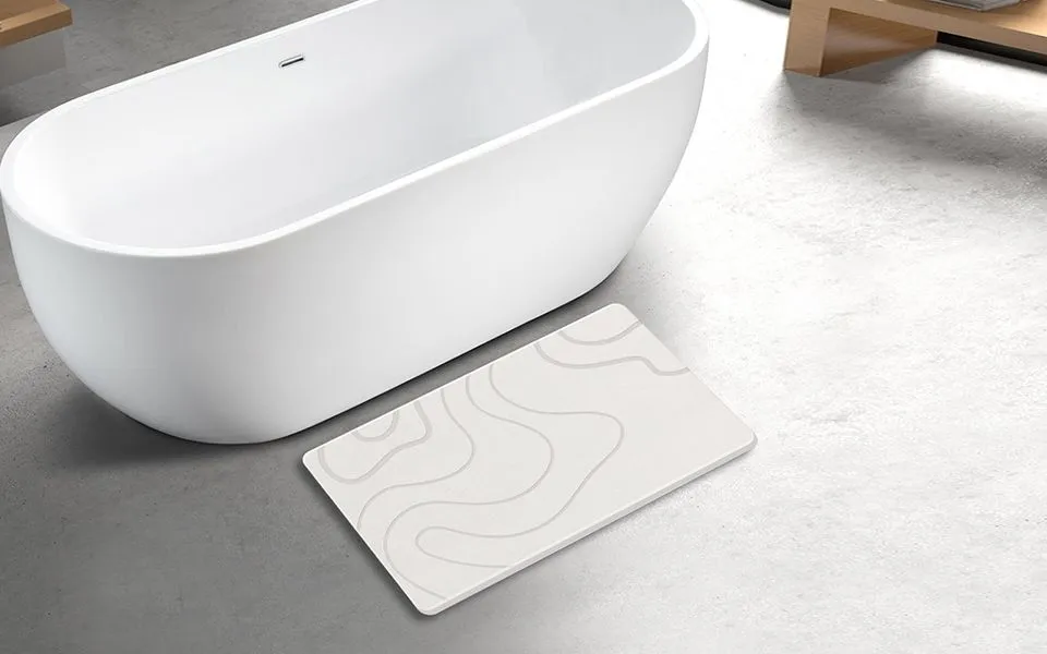 ZIKIBL stone bath mat in White, contour pattern, beside a bathtub