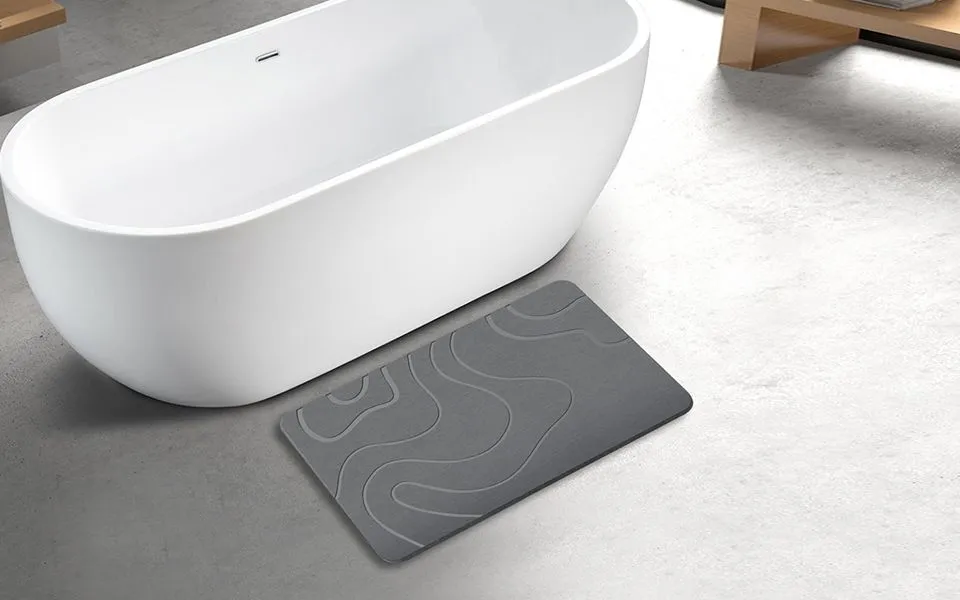 ZIKIBL stone bath mat in Grey, contour pattern, beside a bathtub
